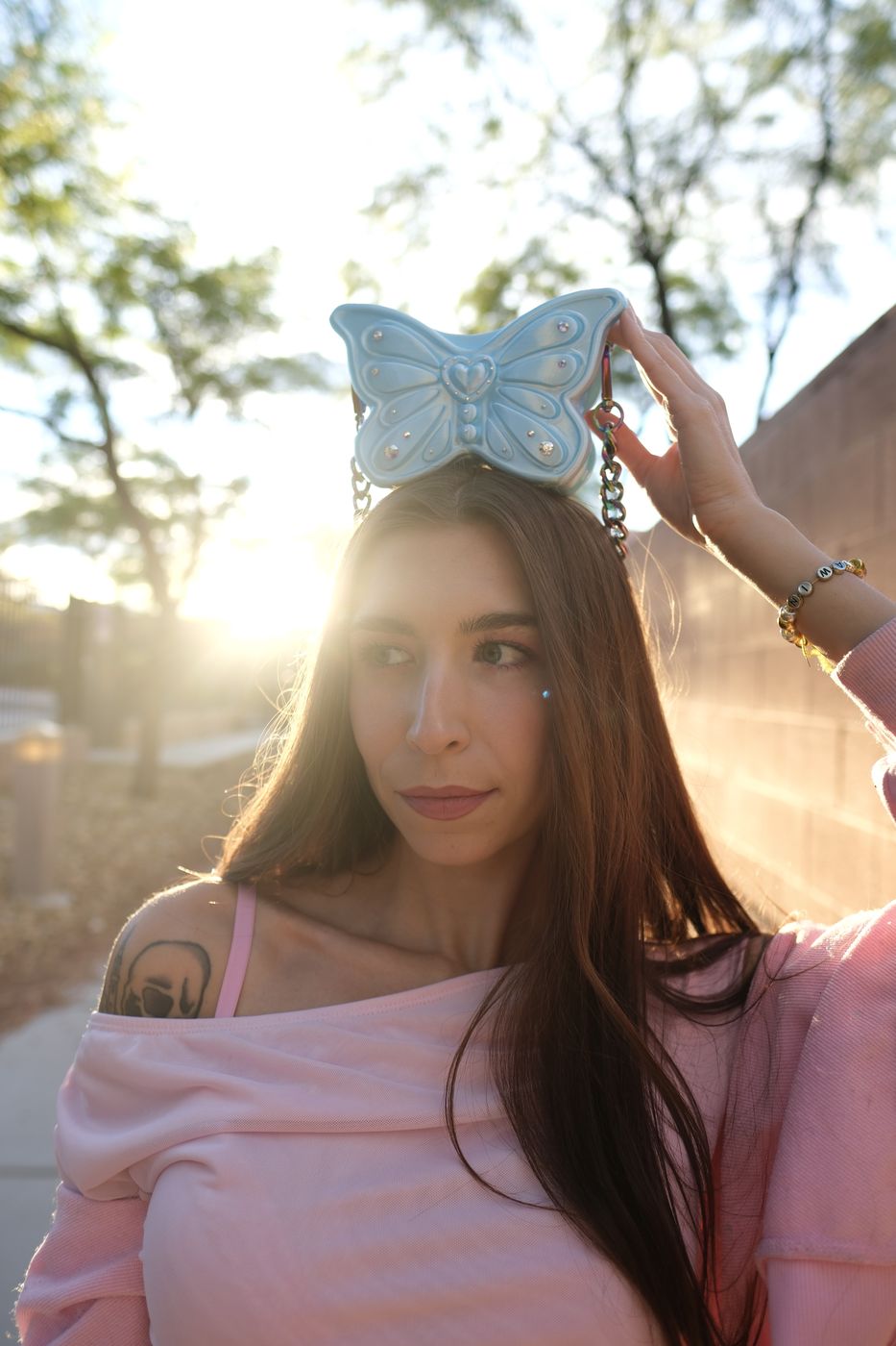 Queen in the golden-hour sun with a baby blue Flutter Bag balanced on her head